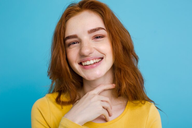headshot-portrait-happy-ginger-red-hair-girl-with-freckles-smiling-looking-camera-pastel-blue-background-copy-space_1258-789